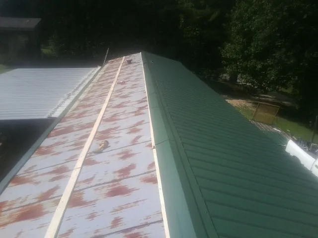 Old rusted panels beside newly installed green metal roofing — Wind Damage Roof Repair by Roofing Brothers in Churchville