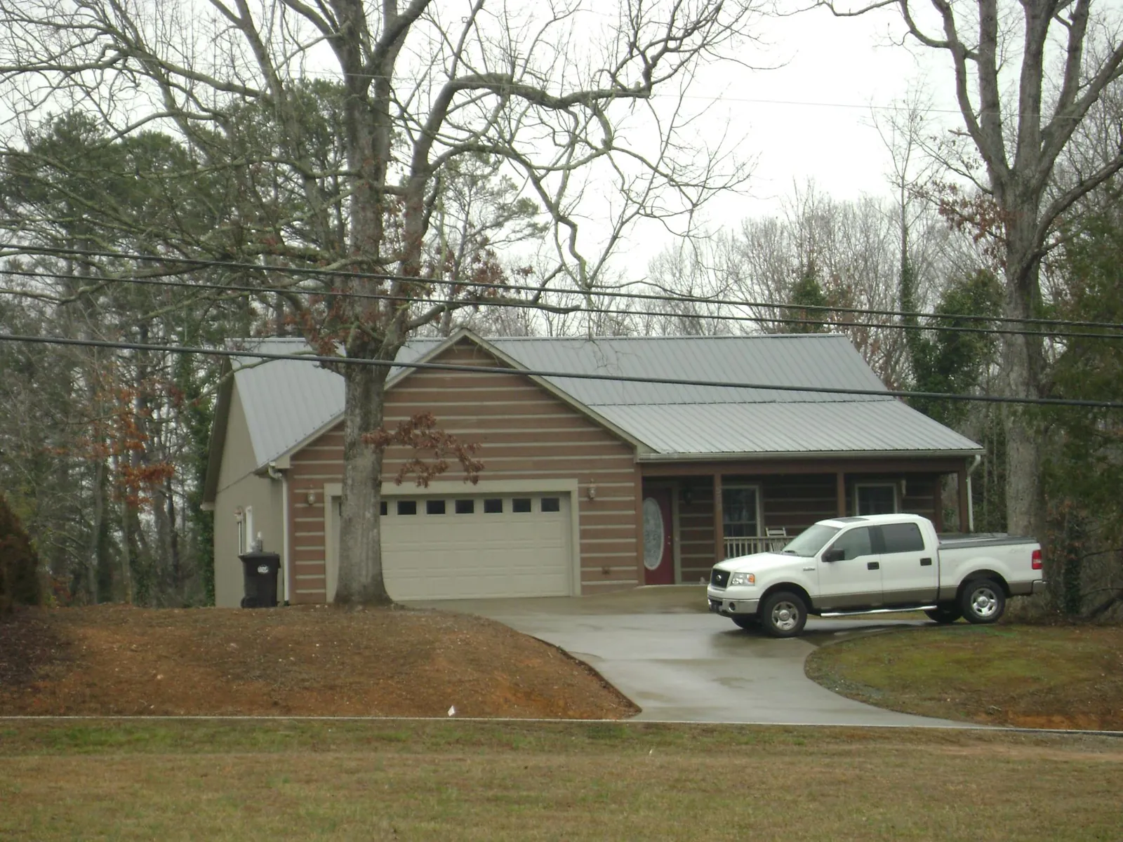Gray metal roof on a log sided house with an attached two car garage in Churchville